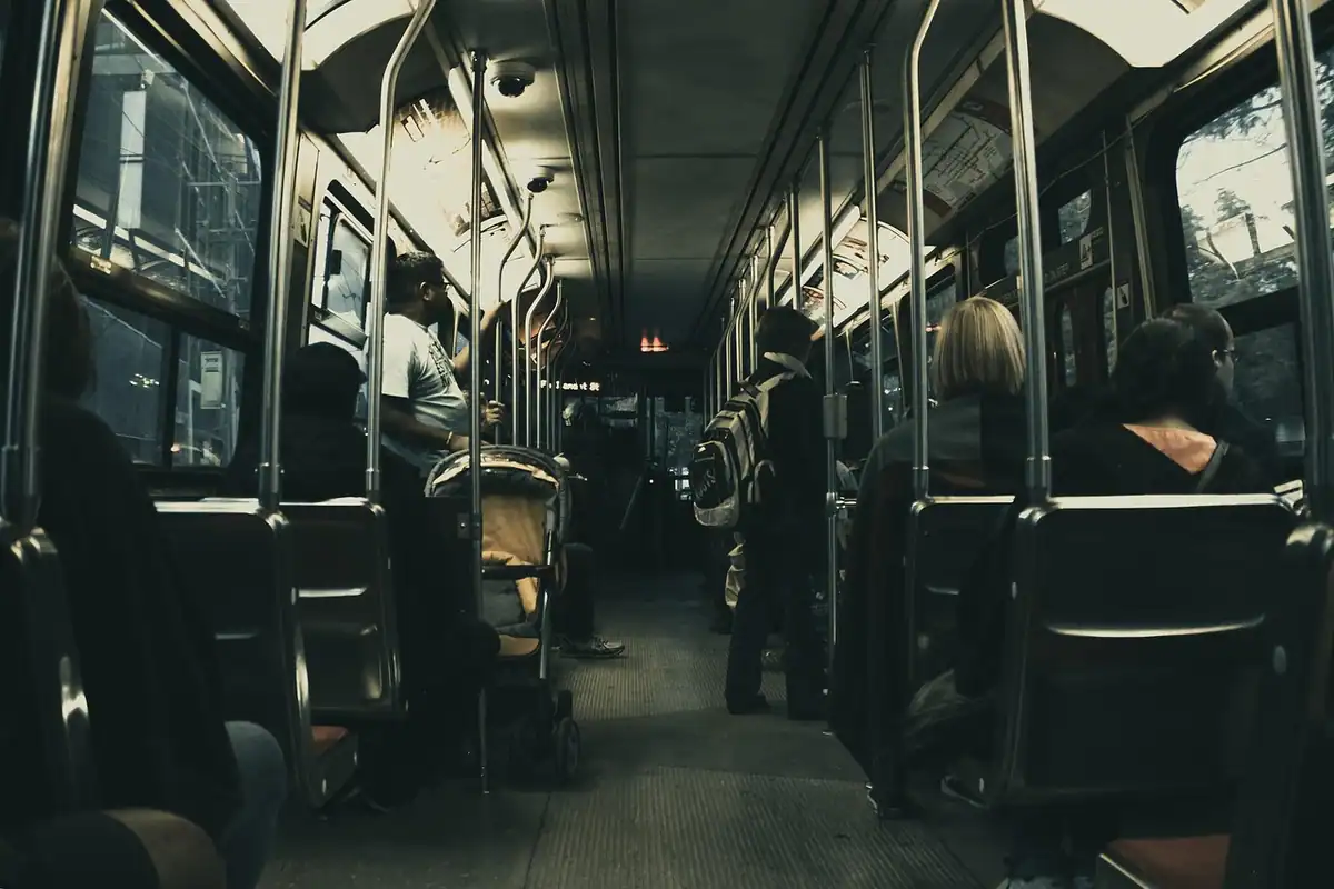 Interior de autobuz cu bare de sprijin și pasageri așezați, pentru transportul persoanelor cu dizabilități