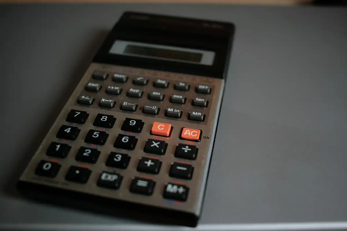 Calculator de birou gri pe o masă, folosit pentru socotirea ajutoarelor și a facturilor casei