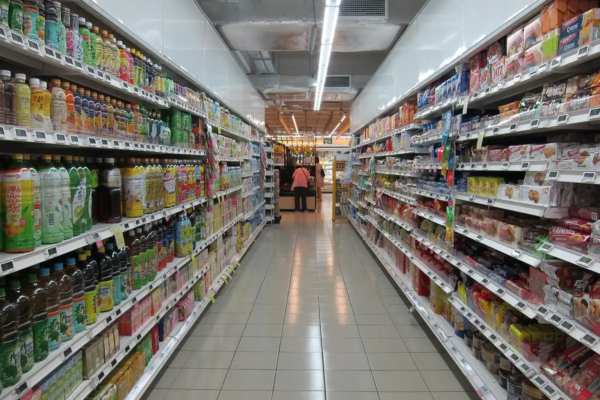 Raft lung de supermarket cu băuturi și produse colorate, unde copiii întâlnesc reclamele