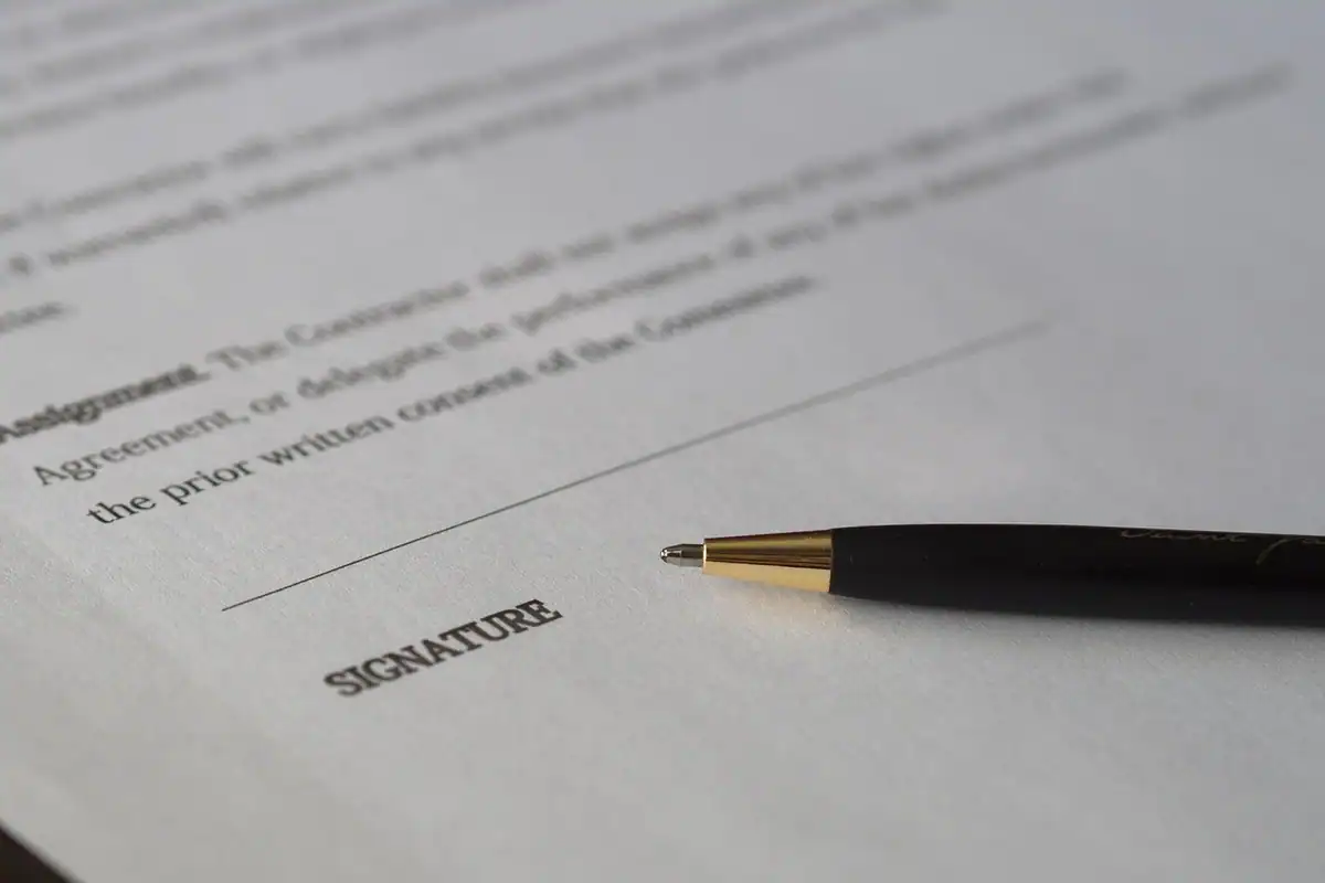 Contract tipărit și un pix auriu lângă linia de semnătură, pentru angajarea după pensionare