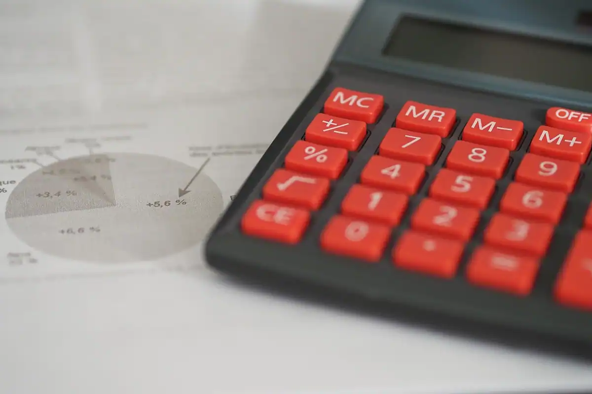 Calculator cu taste roșii așezat pe un document cu grafic circular, pentru calculul deducerilor