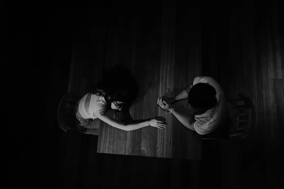 Două persoane la o masă, văzute de sus, într-o discuție liniștită despre banii familiei