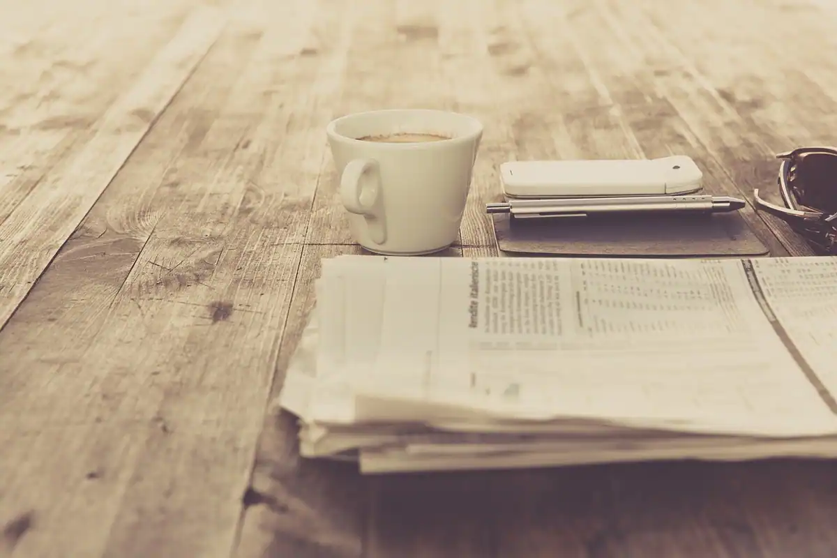 Ceașcă și un teanc de documente pe o masă veche de lemn, cu fluturașul de salariu
