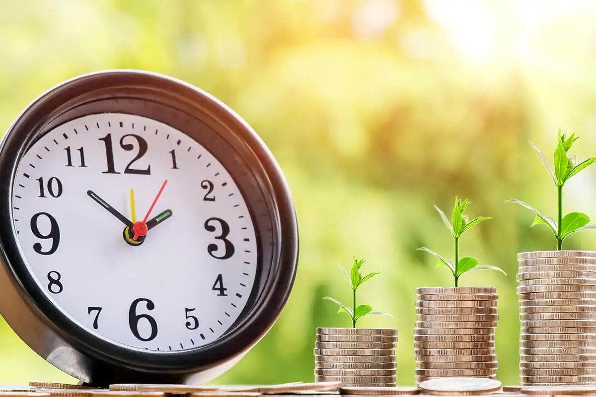 Ceas rotund lângă trei grămezi de monede din care cresc plante mici, simbol al economiilor